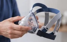 Hands holding a CPAP mask and its headgear straps to check the fit